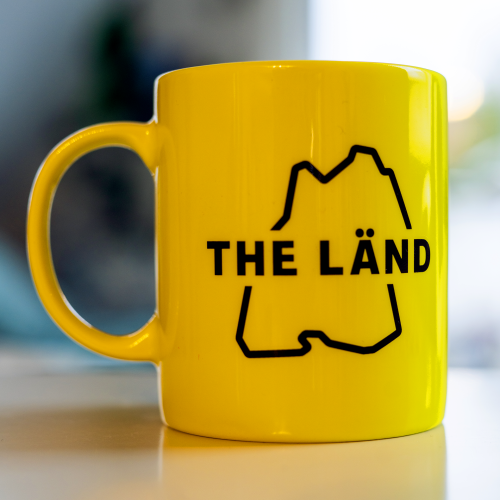 Gelbe Tasse mit THE LÄND Logo