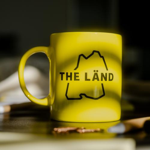 Gelbe Tasse mit THE LÄND Logo