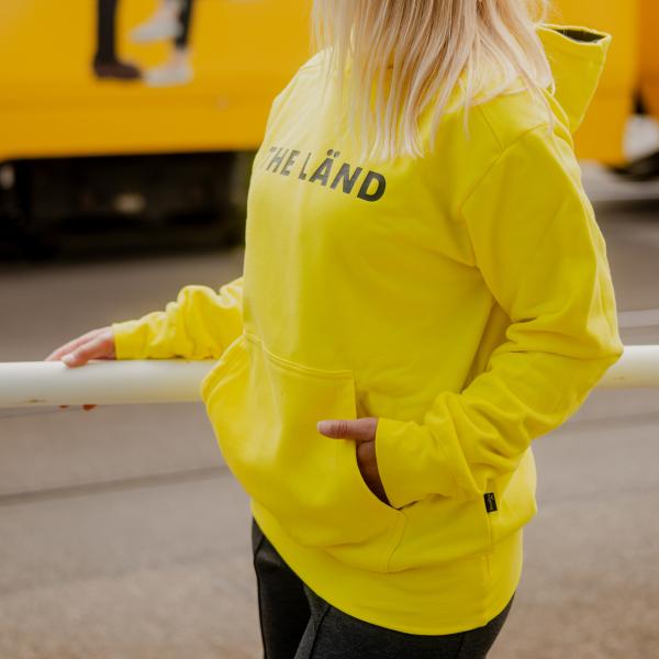 Gelber Kapuzenpullover mit der Aufschrift THE LÄND