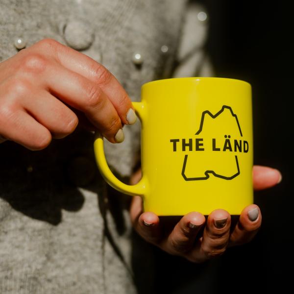 Gelbe Tasse mit THE LÄND Logo
